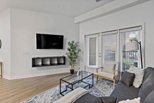 a living room with a couch and a tv on a wall at Spacious 2BD - 5 Min DT, Gym, Parking, W-D - Sleep 12 in Charlotte