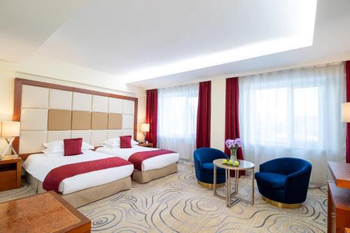 a hotel room with two beds and a table and chairs at Kempinski Hotel Khan Palace in Ulaanbaatar