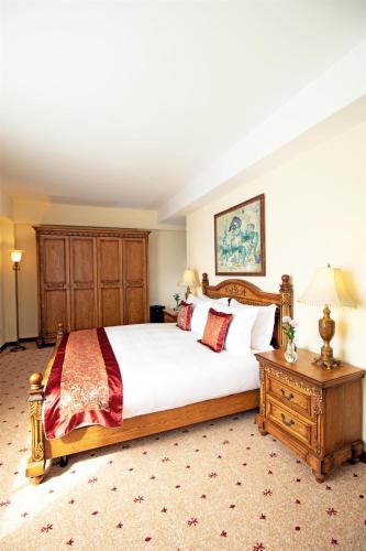 a bedroom with a large white bed and a wooden dresser at Kempinski Hotel Khan Palace in Ulaanbaatar