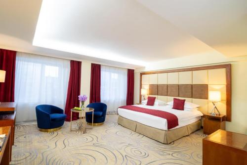 a hotel room with a bed and two blue chairs at Kempinski Hotel Khan Palace in Ulaanbaatar