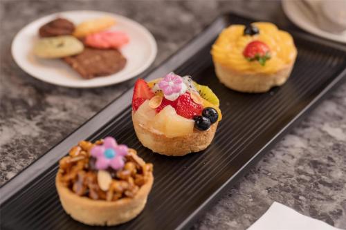 a black tray with four pastries on a table at Kempinski Hotel Khan Palace in Ulaanbaatar