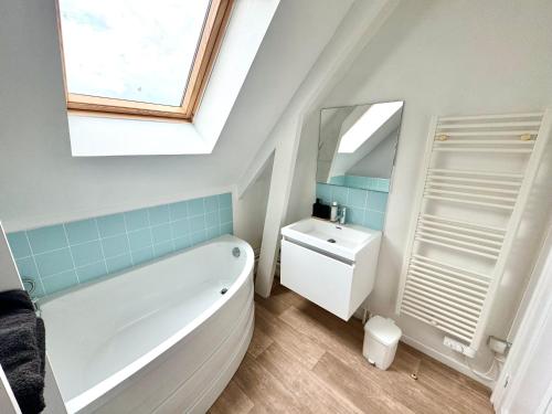 une salle de bain avec une baignoire, un lavabo et un miroir dans l'établissement La Petite Matelote Appartement lumineux - vue Cathédrale, à Boulogne-sur-Mer