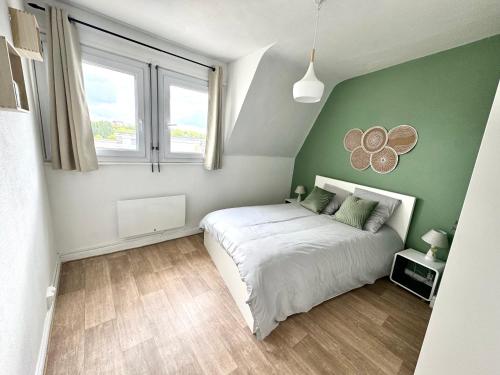 une chambre avec un lit blanc et un mur vert dans l'établissement La Petite Matelote Appartement lumineux - vue Cathédrale, à Boulogne-sur-Mer