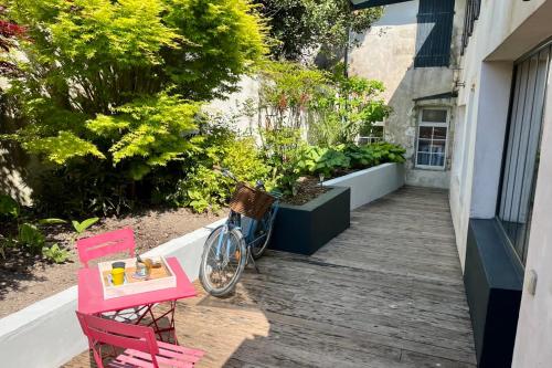 een fiets geparkeerd op een veranda met een tafel en stoelen bij L'Hermione - Room in the heart of St Martin de Ré in Saint-Martin-de-Ré