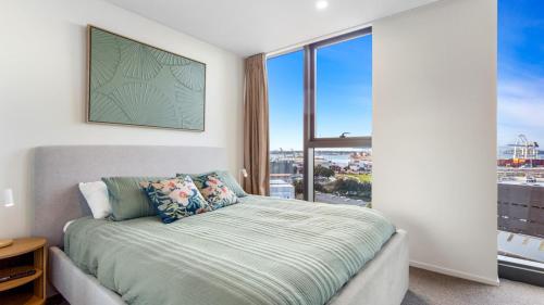 a bedroom with a bed and a large window at QV Stays Modern City Apartment in Auckland