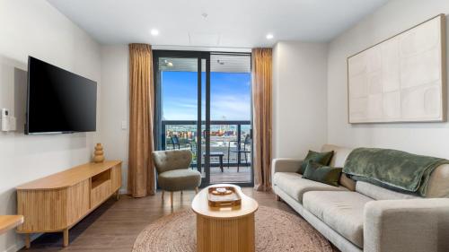 a living room with a couch and a tv at QV Stays Modern City Apartment in Auckland