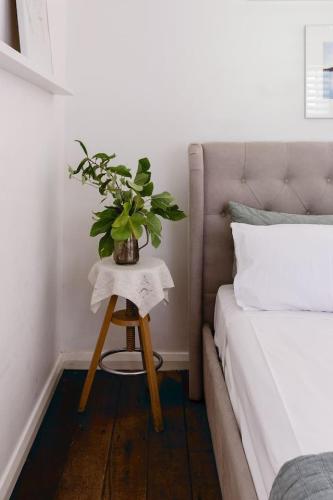 a table with a plant on it next to a bed at The Farmhouse, elegance in the Margaret River coastal countryside in Rosa Brook