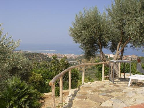 a stone path with a bench and trees and the ocean at Giardino Di Sicilia in SantʼAgata di Militello