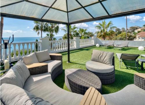 d'une terrasse avec un canapé et des chaises donnant sur l'océan. dans l'établissement Luxury villa face to the sea - swimming pool, à Cannes