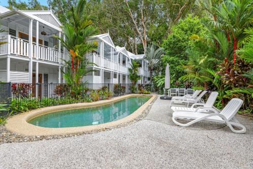 a house with a swimming pool and two lounge chairs at The Queenslander Family Townhouse Near Four Mile Beach in Port Douglas