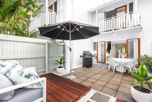 a patio with an umbrella and a table at The Queenslander Family Townhouse Near Four Mile Beach in Port Douglas