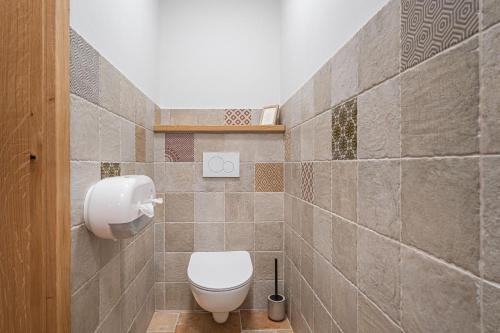 a bathroom with a toilet and a tiled wall at Homestead Kunigunda in Celje
