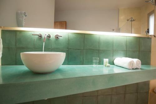 a bathroom counter with a sink and a glass at Amalinas Hotel in San Lorenzo