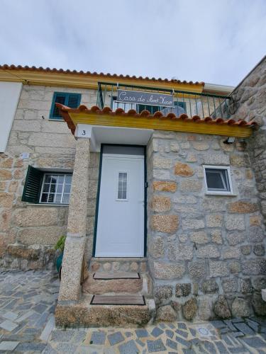 a stone house with a white door on it at Casa do Avô Xico in Sabugal