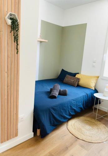 a bedroom with a bed with blue sheets and a table at Le 32 - Studio rénové - Centre in Coudekerque-Branche