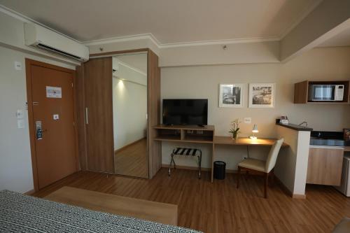a bedroom with a desk and a television and a room at Matiz Vilaboim Ribeirão Preto in Ribeirão Preto