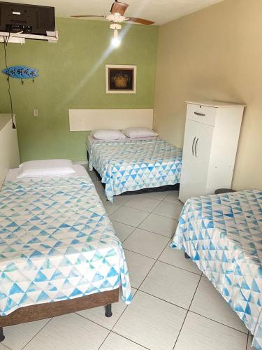 three beds in a room with green walls at Pousada Cantinho da Nilza in Cabo Frio