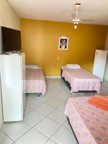 a hotel room with three beds and a tv at Pousada Cantinho da Nilza in Cabo Frio