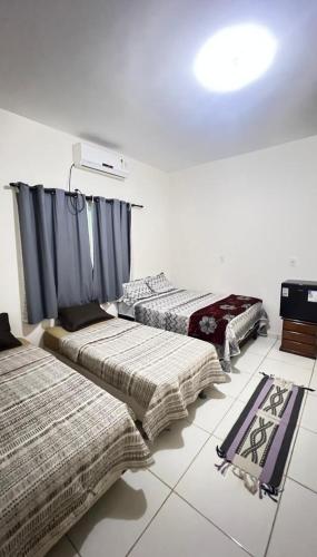 three beds in a room with blue curtains at Pousada riacho santa cruz in Barreirinhas