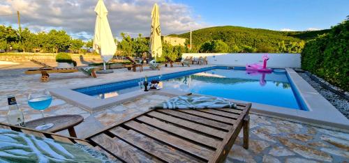 a swimming pool with a bench and a table and a glass of wine at Villa Ana with a private pool on a 3000m2 property in Čvrljevo