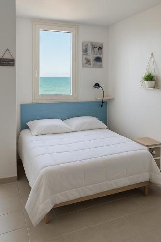 une chambre avec un grand lit avec une fenêtre dans l'établissement Rêve Marin, vue imprenable sur l'océan, à Saint-Hilaire-de-Riez