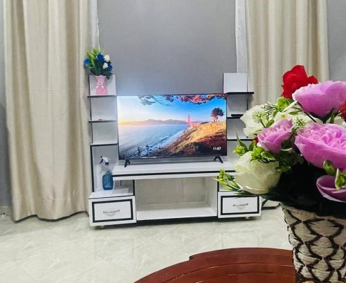a flat screen tv on a entertainment center with flowers at Hanso Furnished Apartments in Kampala