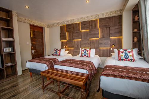 a room with three beds and a bench in it at Valle Del Sol in Urubamba