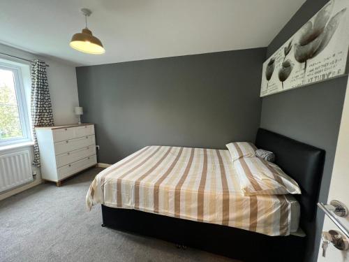a bedroom with a bed with a striped comforter at Tuffley 4 bedroom house in Quedgeley