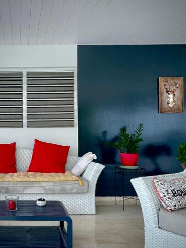 a living room with a white couch with red pillows at Villa Rose Marie Calme et Grands Espaces in Le François