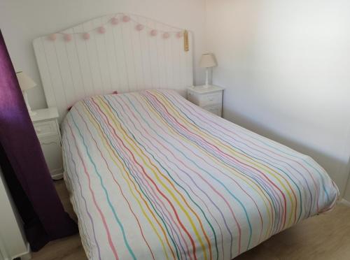 un lit avec une couette à rayures multicolores dans une chambre dans l'établissement Appartement proche Bordeaux, à Cenon