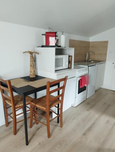 une cuisine avec une table et des chaises et un micro-ondes dans l'établissement Appartement proche Bordeaux, à Cenon