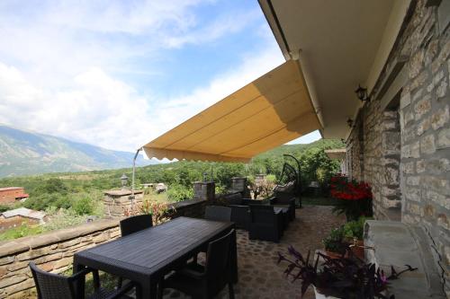 a patio with a table and chairs and an umbrella at Guest House Mehmeti in Tolar