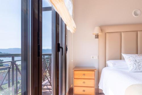 a bedroom with a bed and a view of a balcony at Apartamentos Rurales de Abelleira in Muros