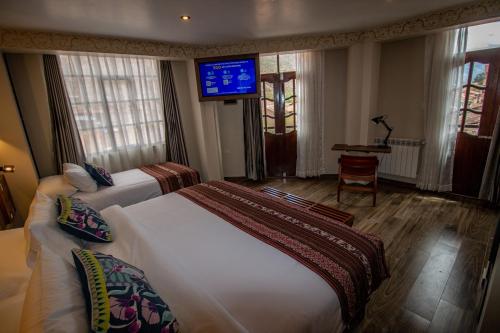 a hotel room with two beds and a flat screen tv at Valle Del Sol in Urubamba