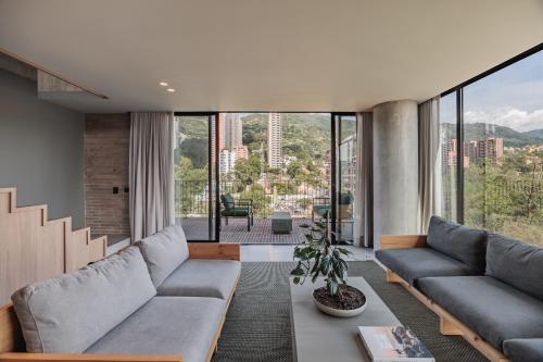 a living room with a couch and large windows at The Somos Loho Hotel in Medellín
