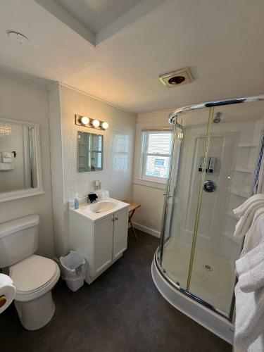 a bathroom with a shower and a toilet and a sink at Yardarm Motel in Searsport