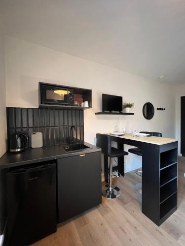 une cuisine avec un comptoir noir et un bureau dans l'établissement Chambre studio centre ville Dol de Bretagne, à Dol-de-Bretagne