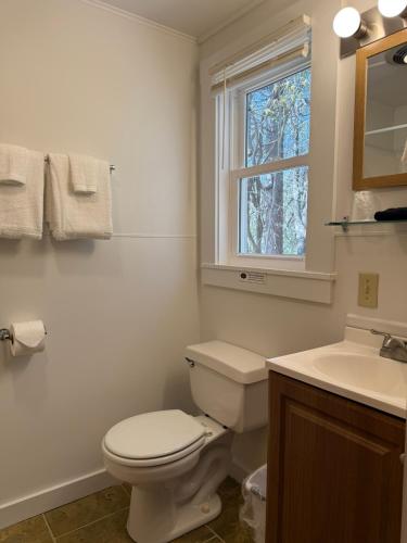 a bathroom with a toilet and a sink and a window at Yardarm Motel in Searsport