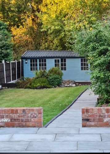 a yard with a blue house with a fence at Stunning property with Summer house in Bescot