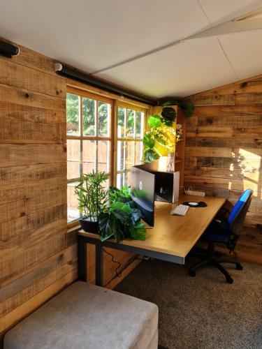 an office with a desk with a computer and plants at Stunning property with Summer house in Bescot
