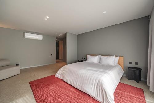 a bedroom with a large white bed with a red rug at The Somos Loho Hotel in Medellín