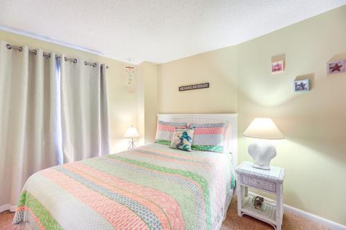 a small bedroom with a bed with a colorful blanket at Walk to Indian Beach Condo with Ocean-View Balcony in Indian Beach