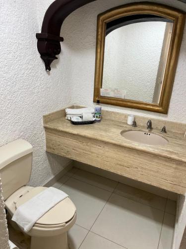 a bathroom with a toilet and a sink with a mirror at Cancun plaza frente al mar in Cancún