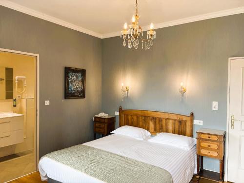 a bedroom with a bed and a chandelier at Logis Hôtel Beau Site in Argelès-Gazost