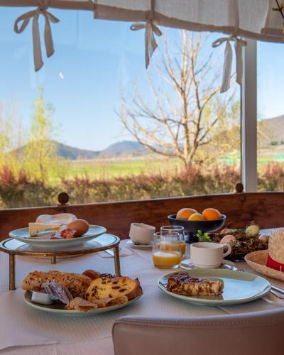 a table with plates of food on it with a window at Hôtel Restaurant Verger des Châteaux, Route des vins Haut-Koenigsbourg in Dieffenthal