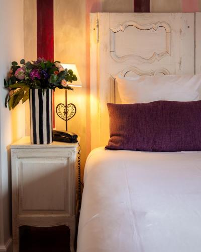 a bedroom with a bed and a vase of flowers on a table at Hôtel Restaurant Verger des Châteaux, Route des vins Haut-Koenigsbourg in Dieffenthal