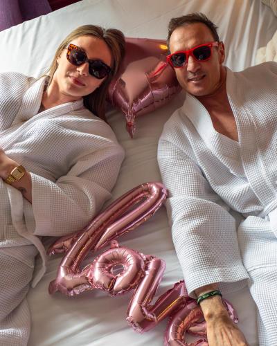 a man and a woman laying on a bed with candyoons at Hôtel Restaurant Verger des Châteaux, Route des vins Haut-Koenigsbourg in Dieffenthal