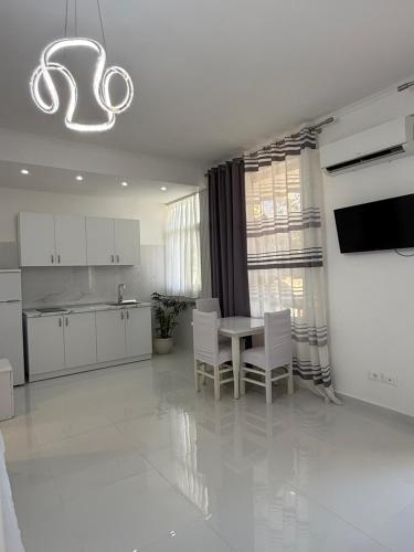 a kitchen with white cabinets and a table and chairs at ELIO's Room in Durrës