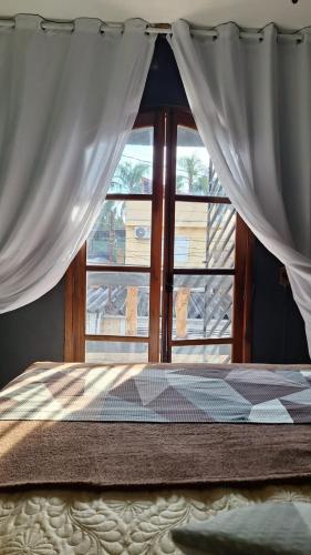 a bed in front of a window with curtains at RustiCidade in São Paulo