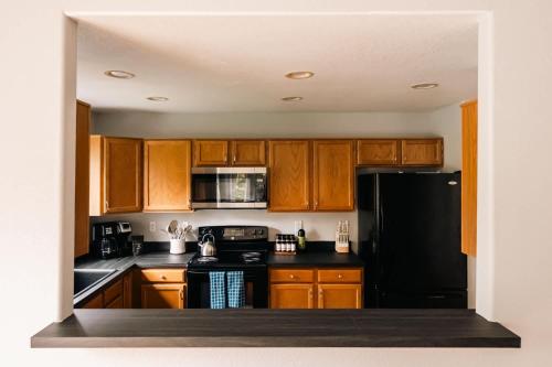 a kitchen with wooden cabinets and a black refrigerator at Cozy Retreat - King Beds - Cinema Cave & Home Gym in Westminster